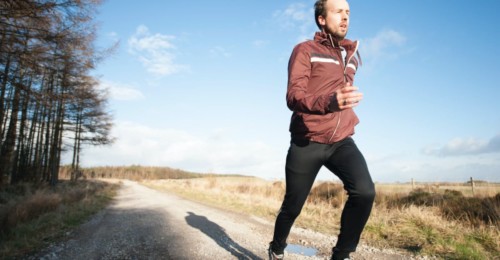 man running nearby a forest and a field